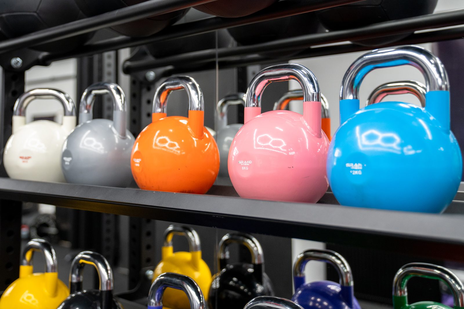 Kolorowe kettlebell na profesjonalnym stojaku