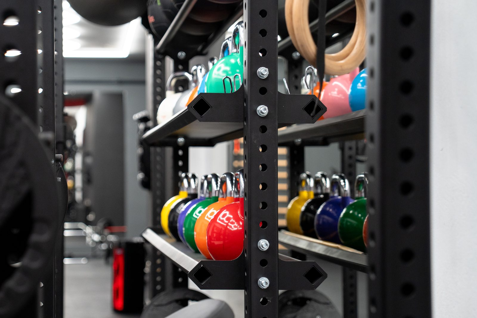 Kolorowe kettlebell i kółka gimnastyczne na racku